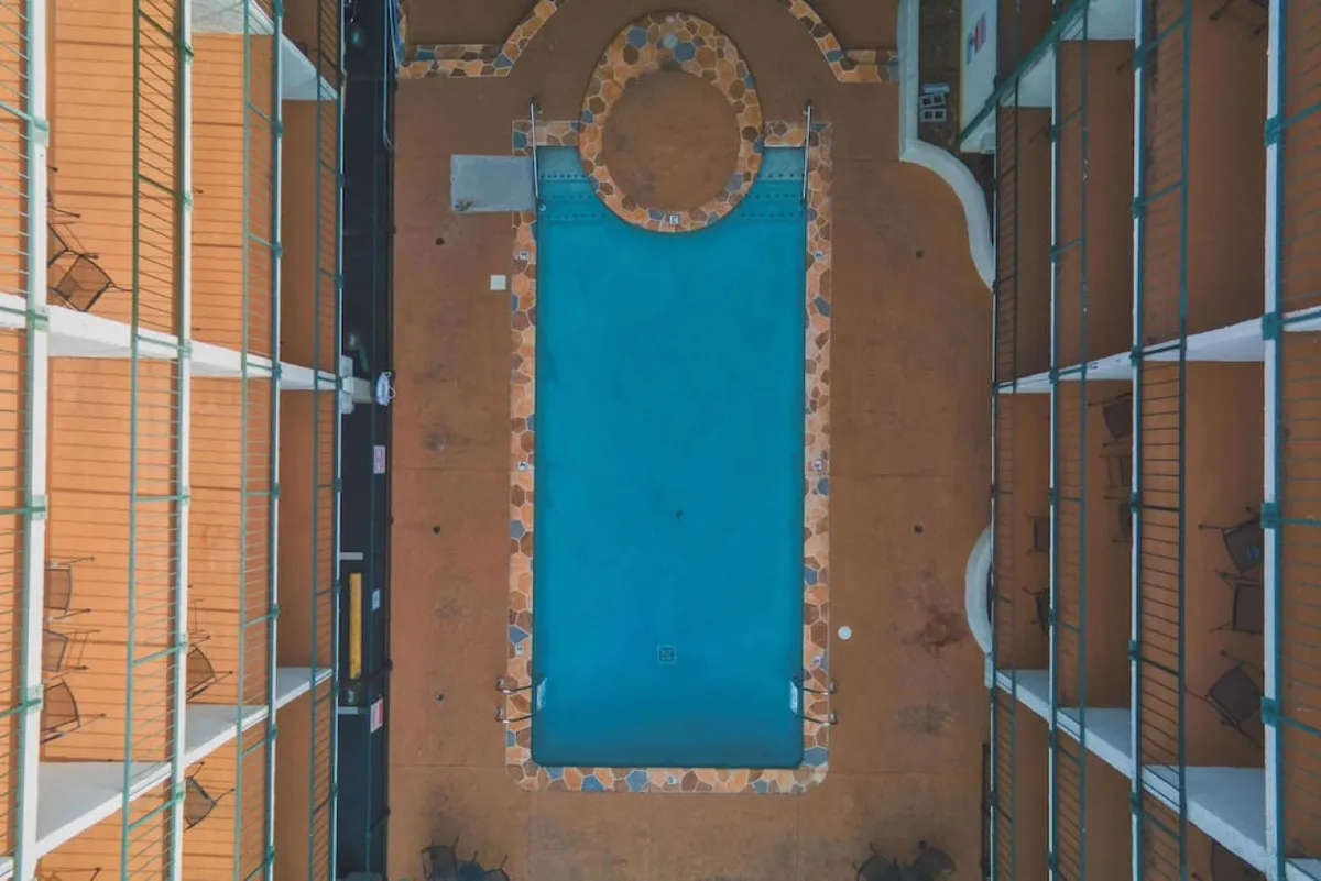 This image depicts the Oak Square swimming pool surrounded by balconies and patio chairs, basking in soft sunlight. The pool is tranquil, inviting guests to unwind, while the environment is leisurely and welcoming—ideal for a relaxing break between busy convention sessions.