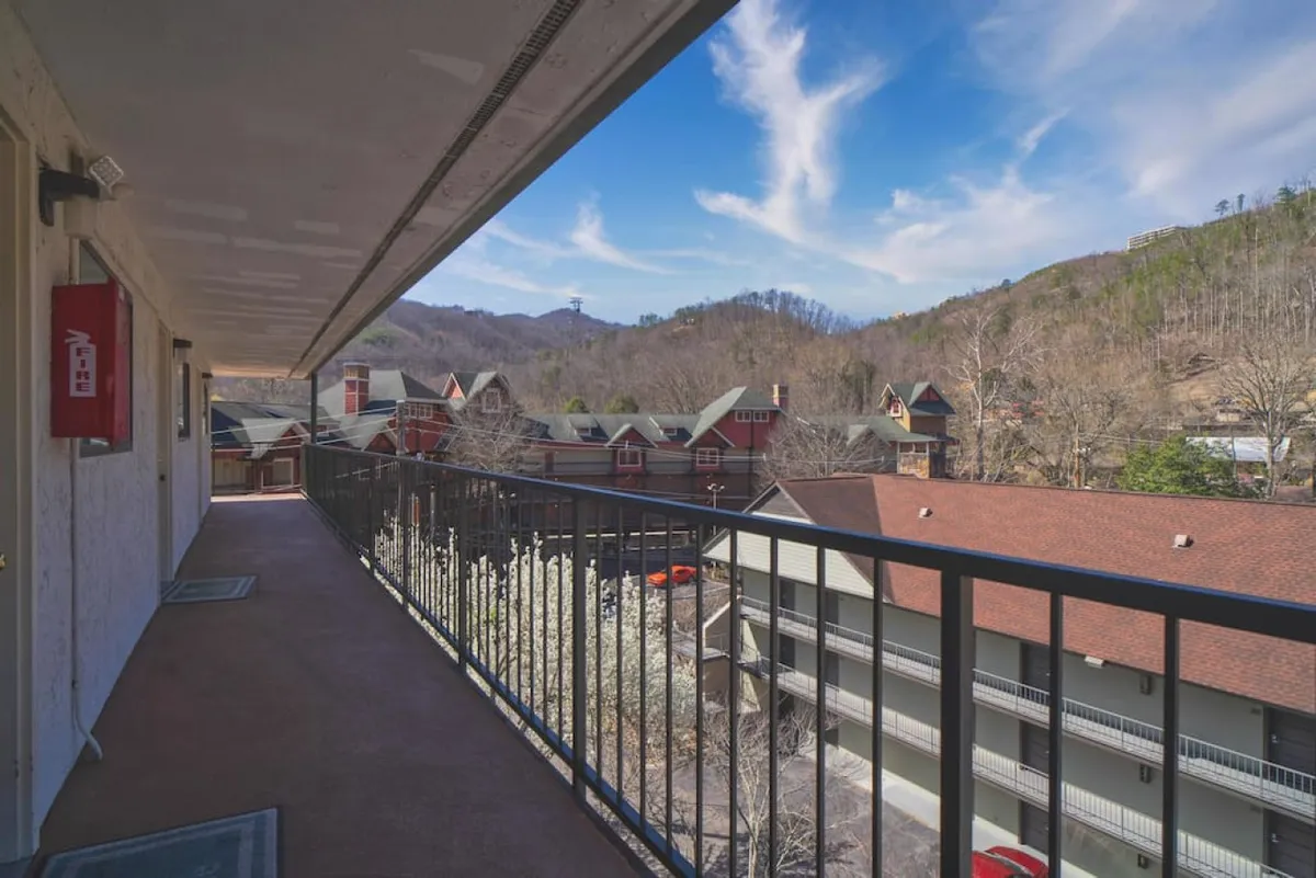 The photo captures a peaceful balcony scene with a mountain view, balcony railing, and friends enjoying the vista. The mood is relaxed and communal, making it ideal for highlighting the property’s proximity to Gatlinburg’s lively scene and its potential for shared moments.